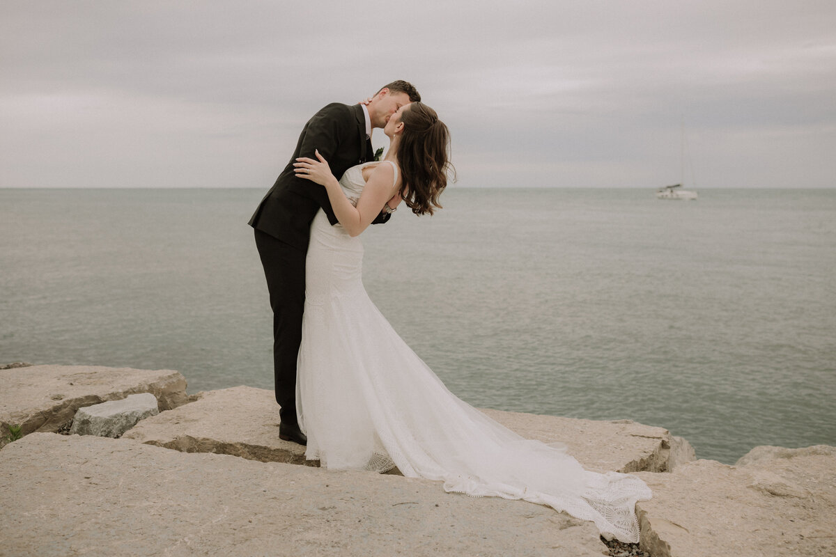wedding couple on rocks at water's edge