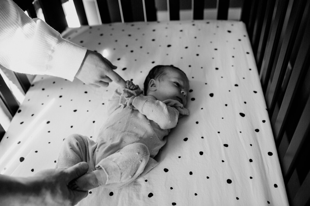 baby-holding-moms-finger-in-crib