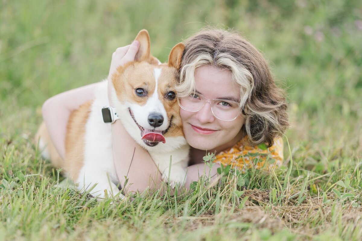 a high school grad posing in the grass with her dog