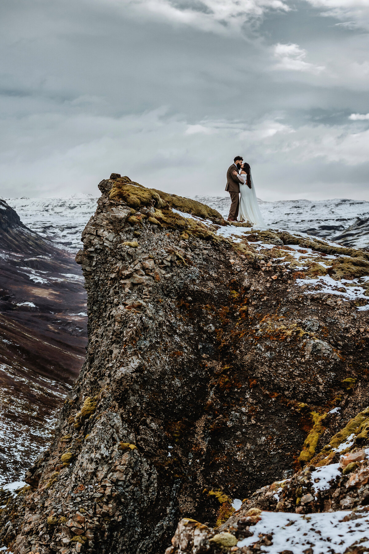 Elegant and wild, a couple embraces tightly amidst a field of Icelandic cotton grass, the wind weaving their love into the landscape.