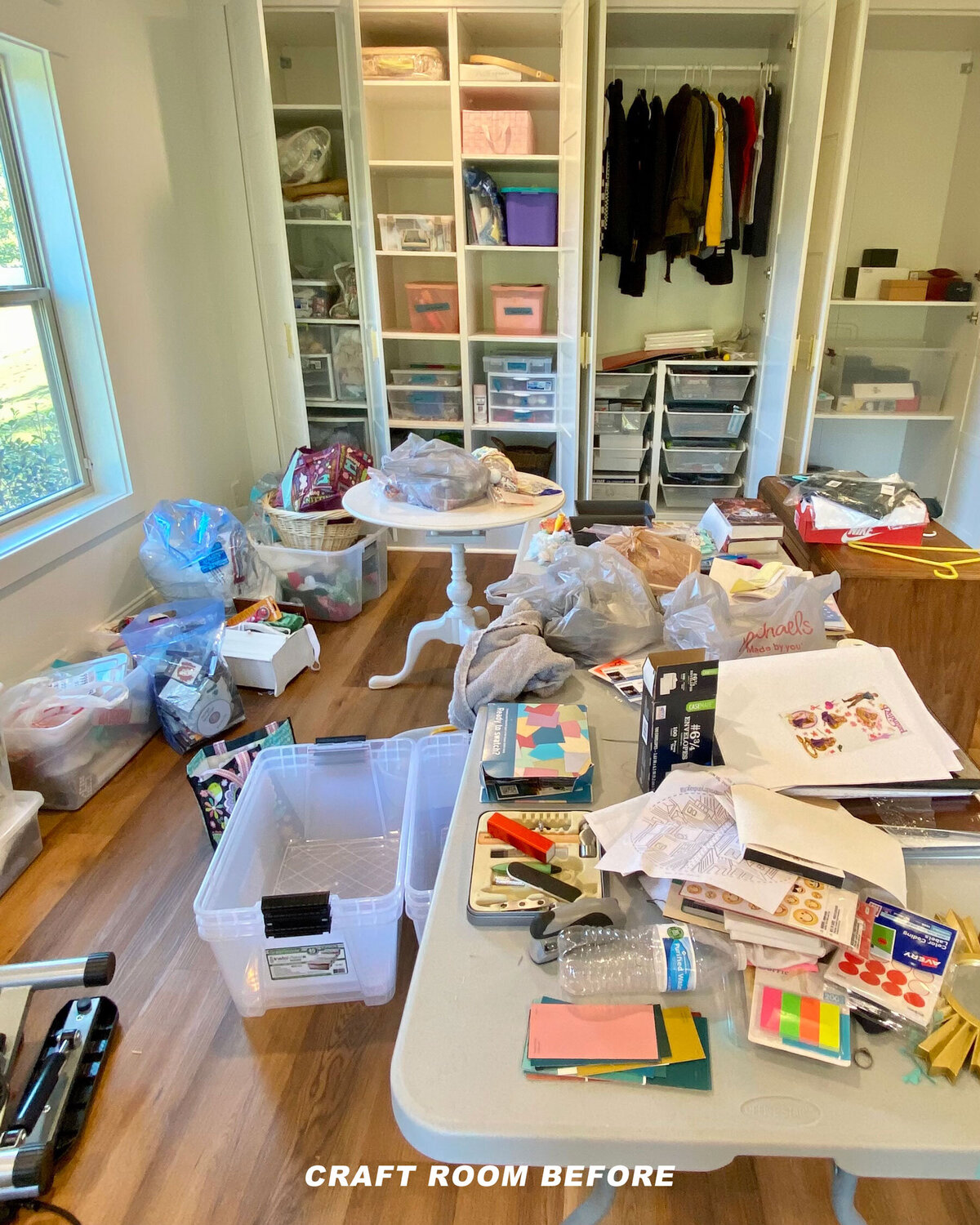 A cluttered craft room with open cabinets and various items scattered on tables and the floor, including boxes, fabric, and craft supplies. Clothing hangs in an open closet, and there are plastic storage drawers. Text reads "CRAFT ROOM BEFORE.
