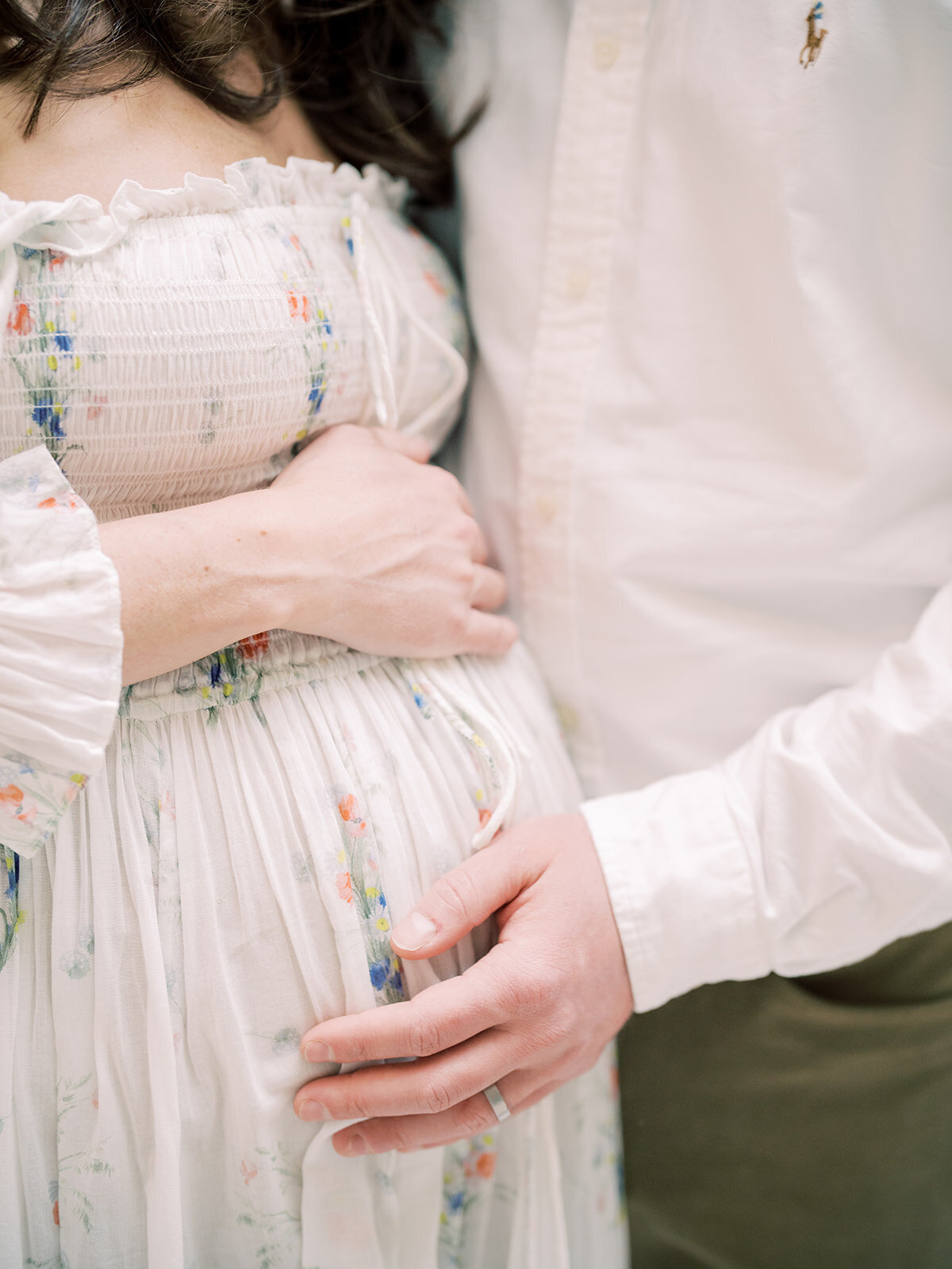Close-up view of pregnant mother and her husband placing their hands on her belly.