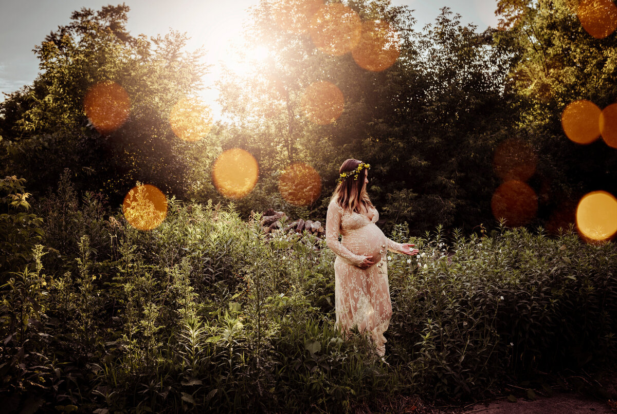 beautiful mother to be embracing sunlight in a field outside in Minnesota