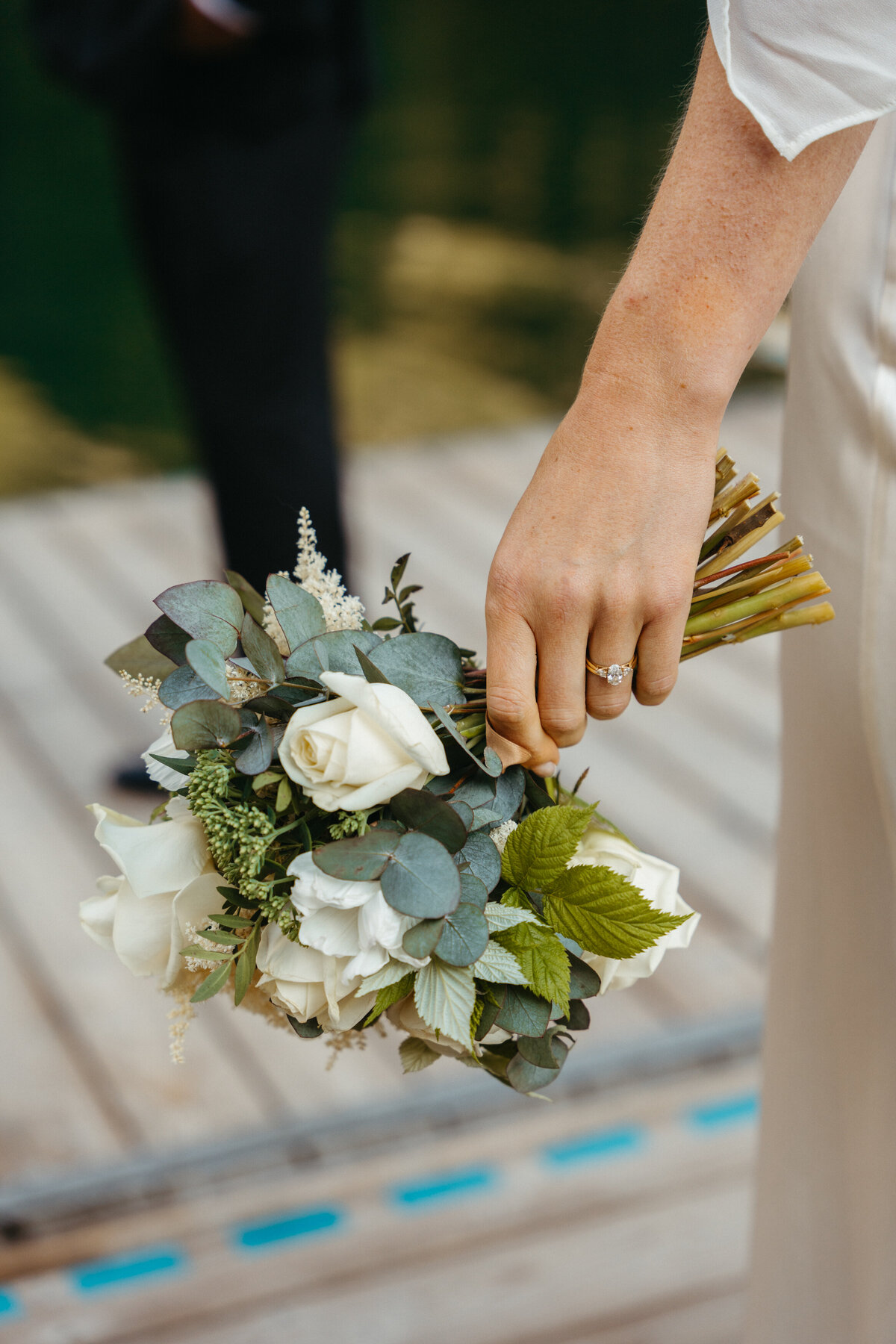 Bride holding white rose bouquet with greenery details