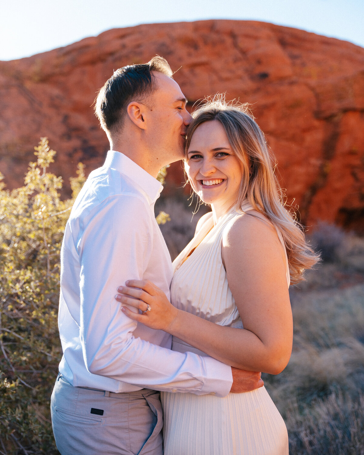 man kisses woman in golden hour light in red rock canyon, nevada