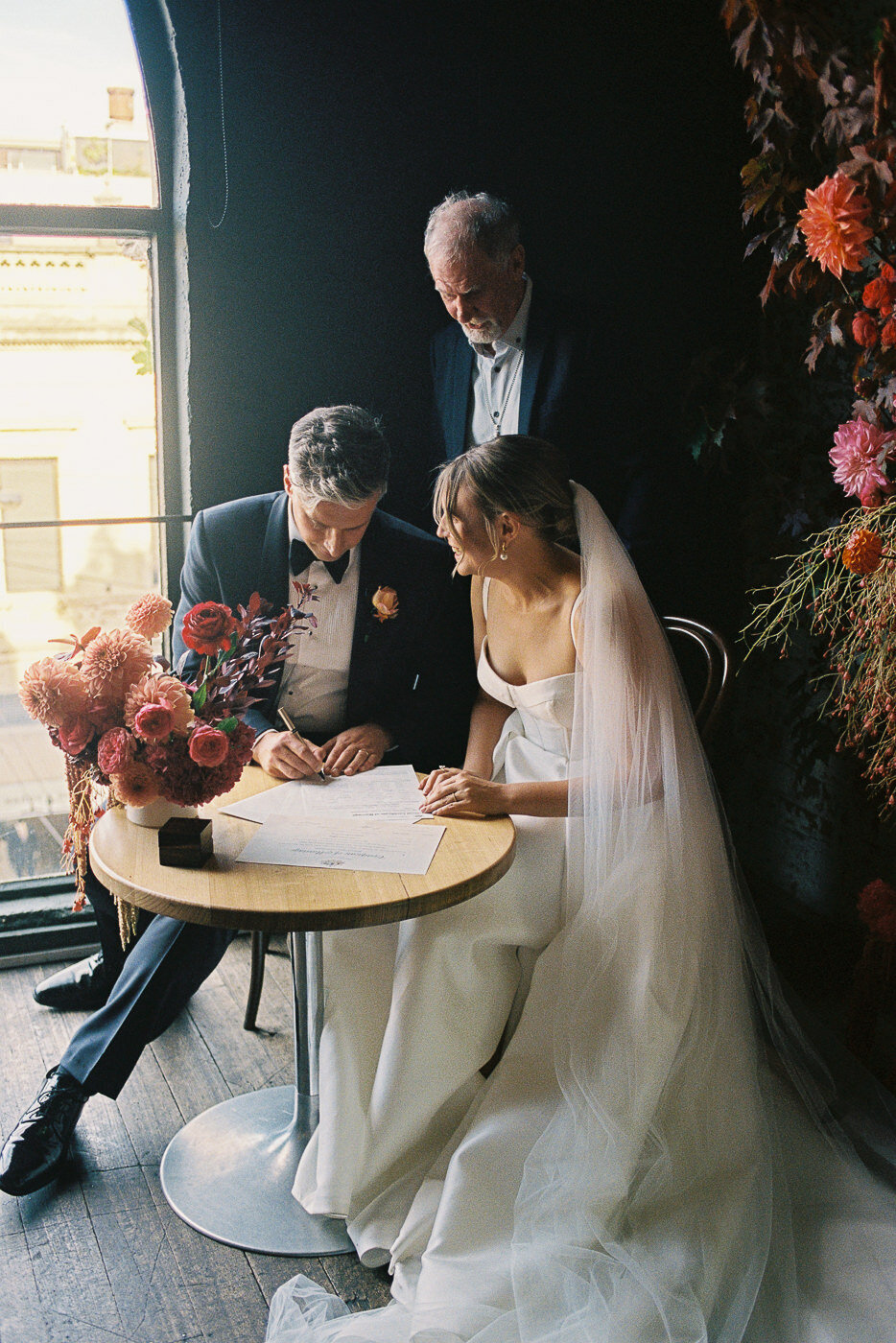 Couple signing their wedding certificate, captured on 35mm film in a relaxed, natural, journalistic style