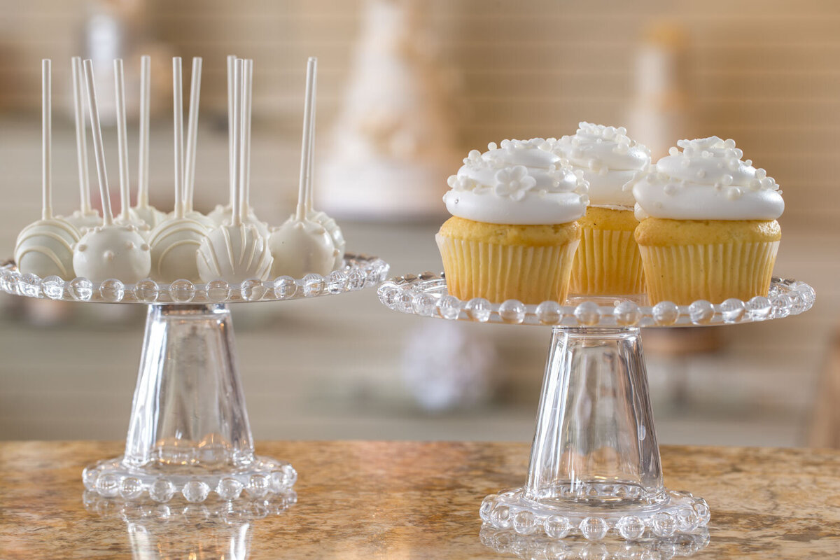 White cake pops and cupcakes on clear stands