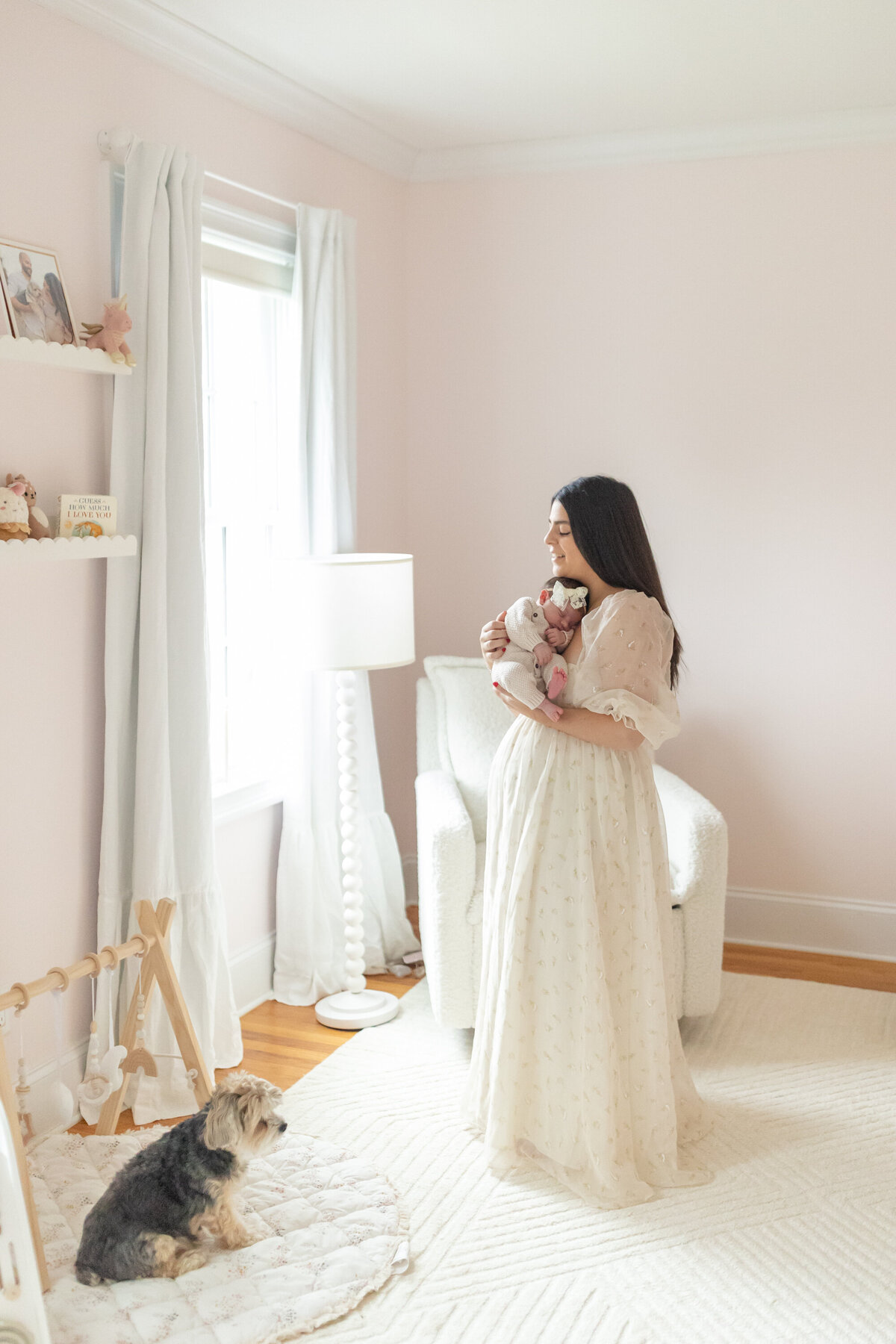 New mother standing at a window in her home nursery, gently holding her newborn baby on her chest. Soft natural light filters through the window, highlighting the intimate and peaceful connection between mother and child
