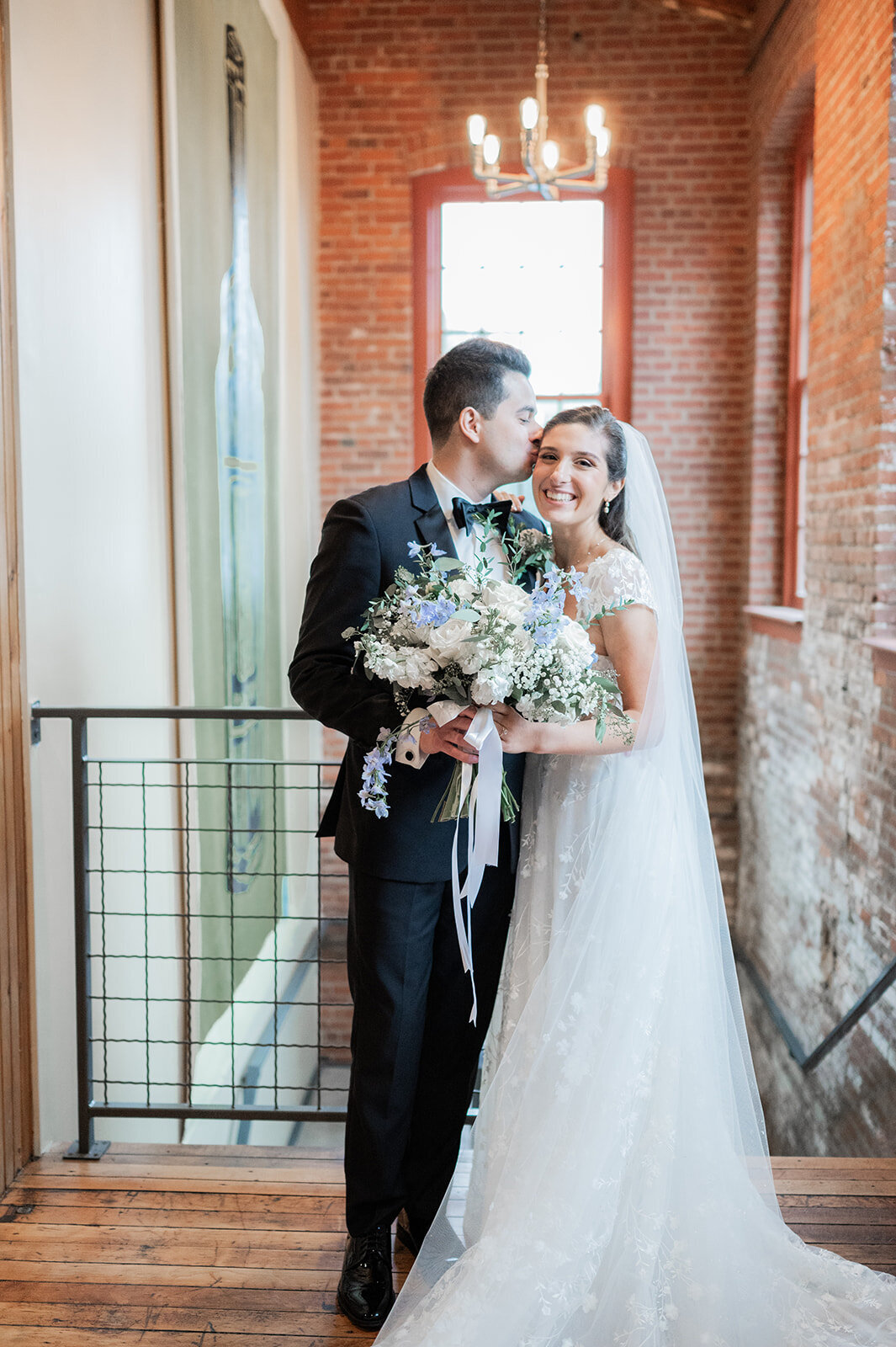 groom plants kiss on his bride during wedding day portraits