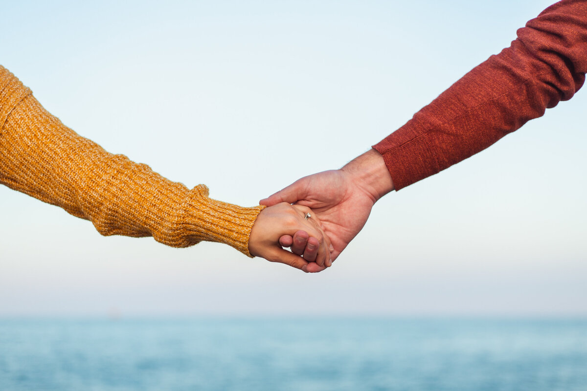 Husband and wife holding hands at the beach.