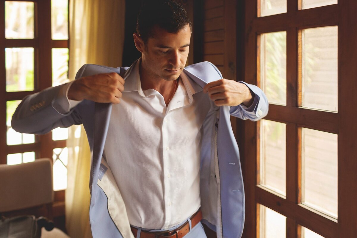 Groom getting ready and putting on jacket for  Riviera Maya wedding.