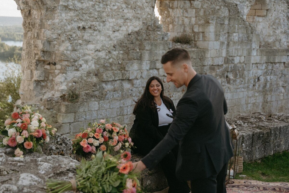 Brendan récupérant une fleur sur l'une des compositions florales. Séance fiançailles dans les ruines d'un château en Normandie par Kamescop.