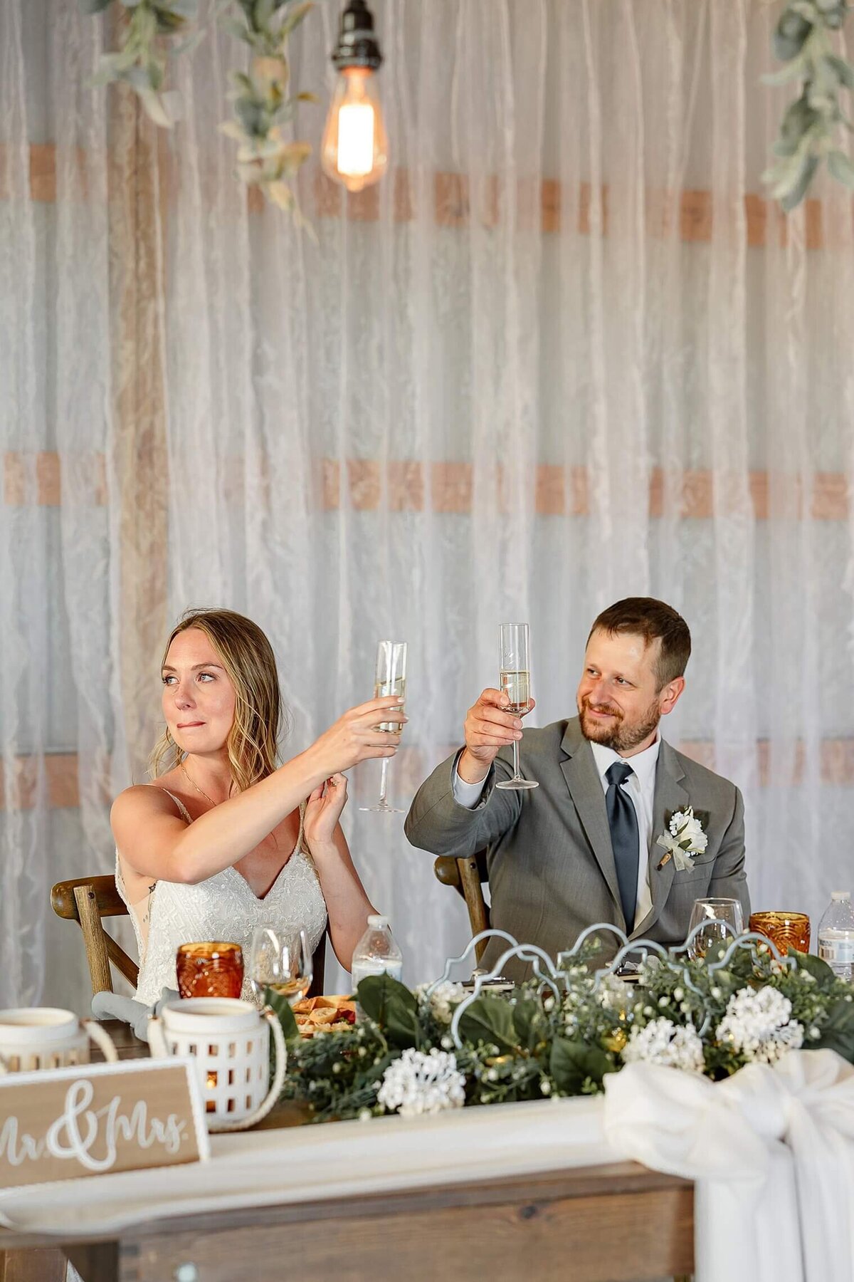 bride and groom cheers at their wedding reception during toasts