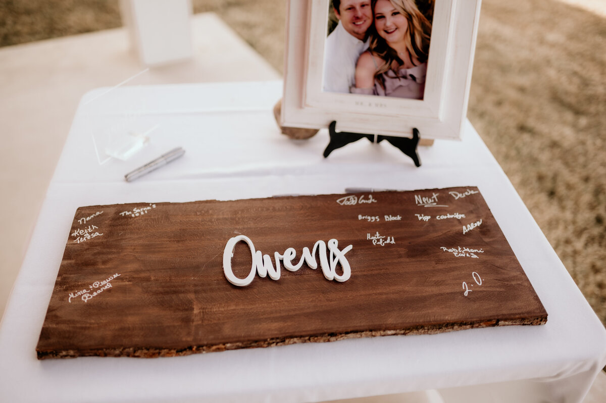wedding sign in board with the couples last name in white lettering with pens for guests to sign