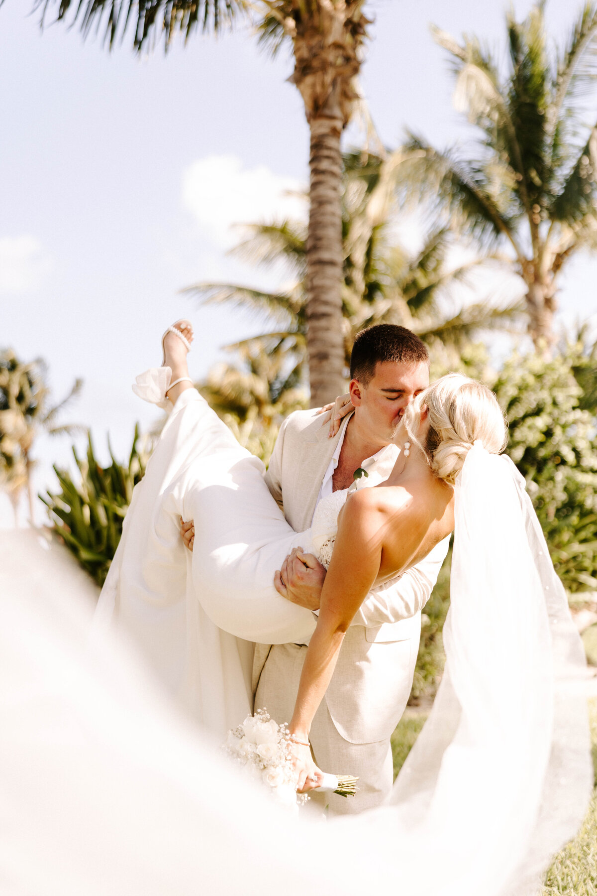 Groom lifts bride and dips her for first kiss at Beachside wedding Cancun, Mexico