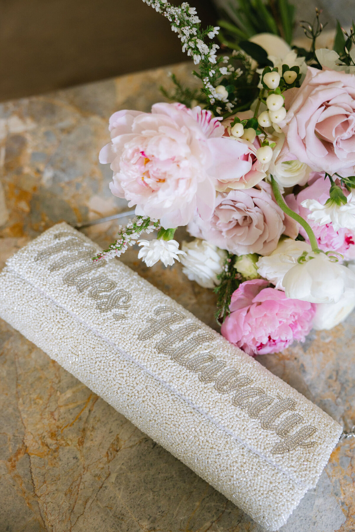 bride’s pink floral bouquet paired with a beaded purse featuring her custom last name at The Adolphus in Dallas, highlighting personalized and elegant wedding details.