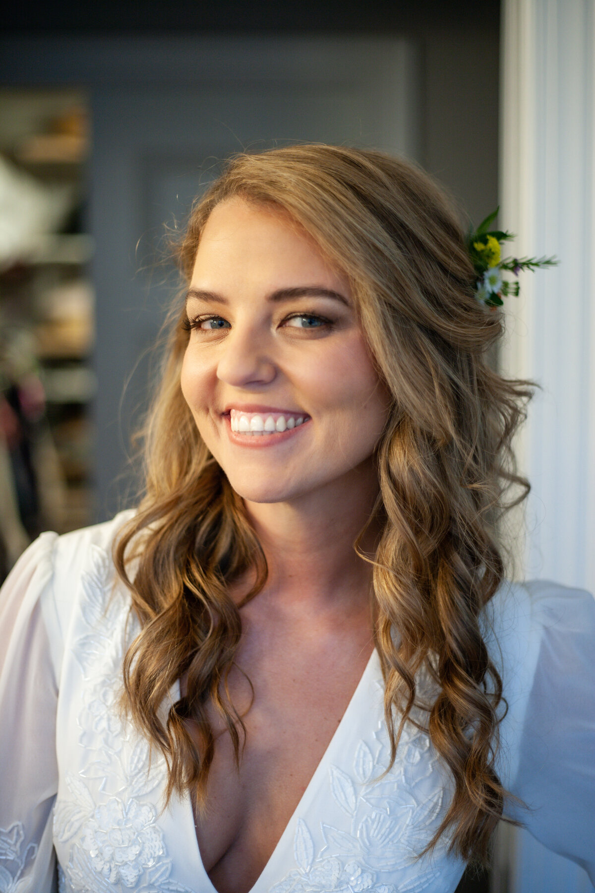 A girl wearing a white dress with sprigs of flowers in her curled hair