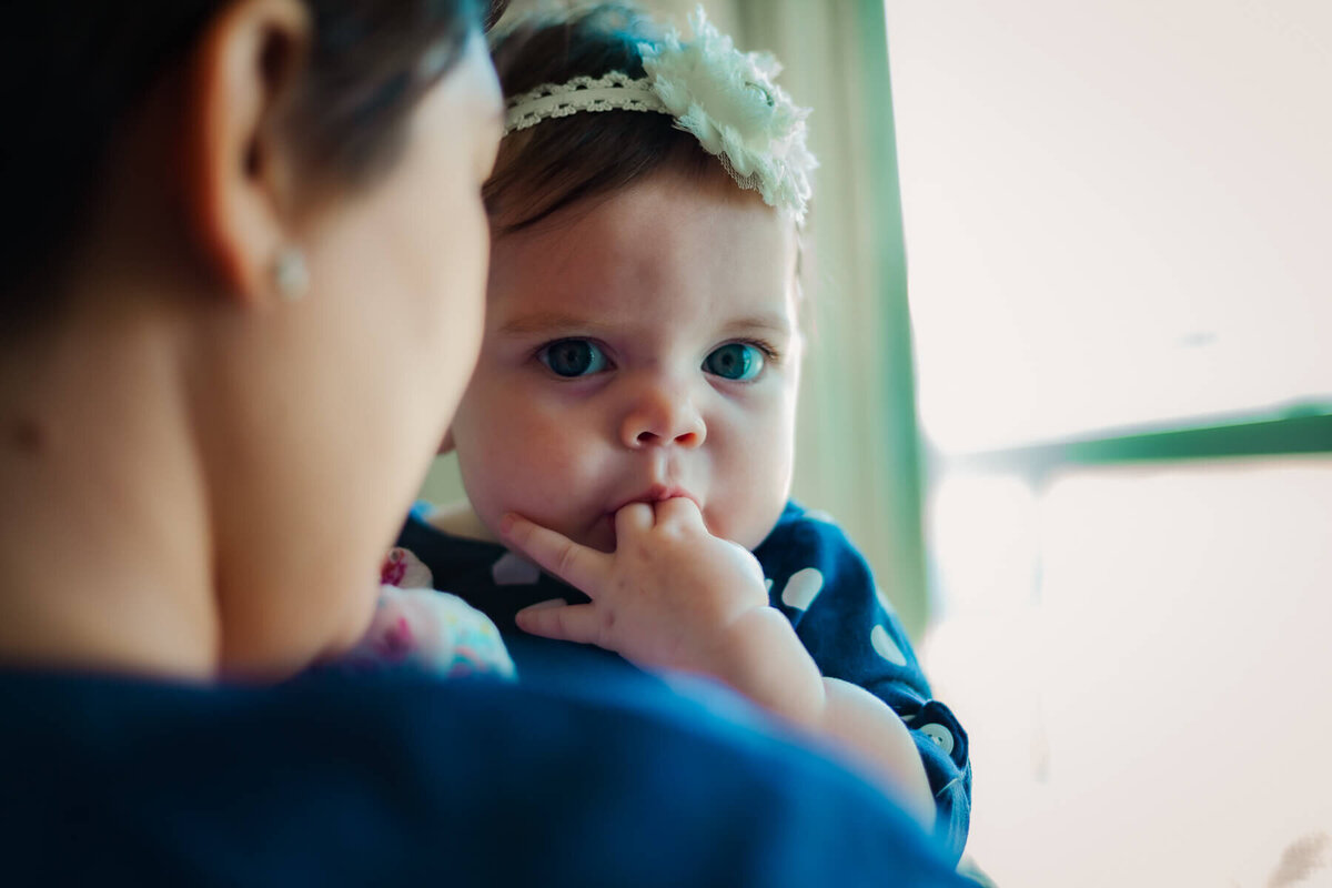 A sweet little girl looks over the shoulder of her mommy with curiosity.