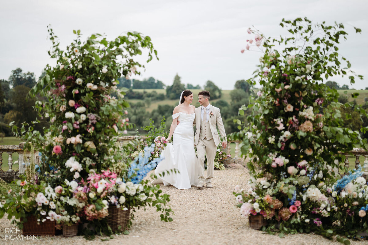 Broken arch of flowers at Orchardleigh Estate. Pink, white and pale blue flowers with baskets