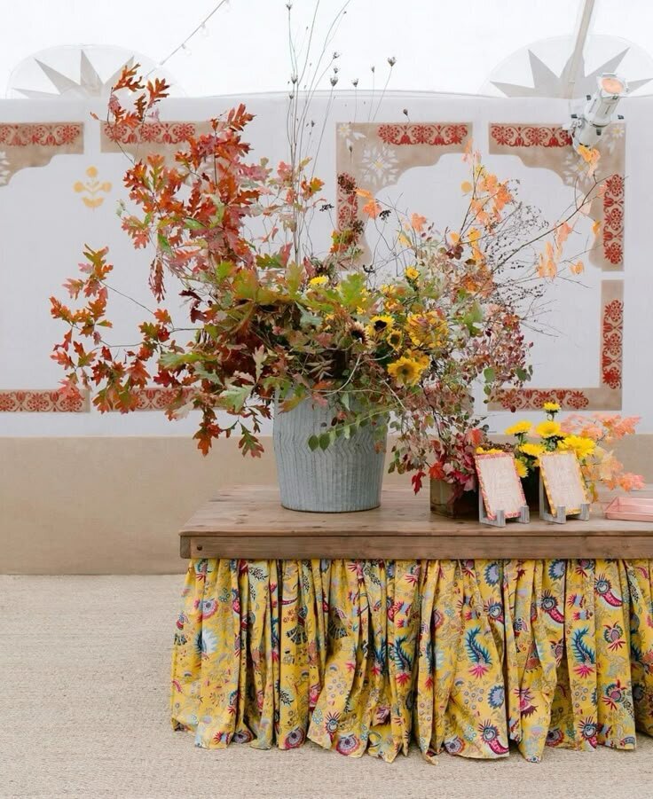 Floral bar display with patterned yellow skirt and citrus-toned flowers, a vibrant cocktail hour look for Airlie Gardens weddings