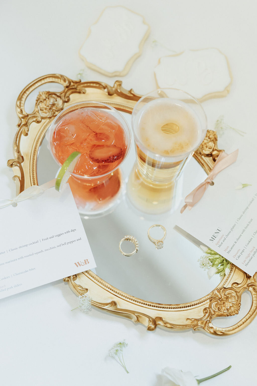 fargo wedding name place cards on flatlay with vintage mirror, rings and beverages
