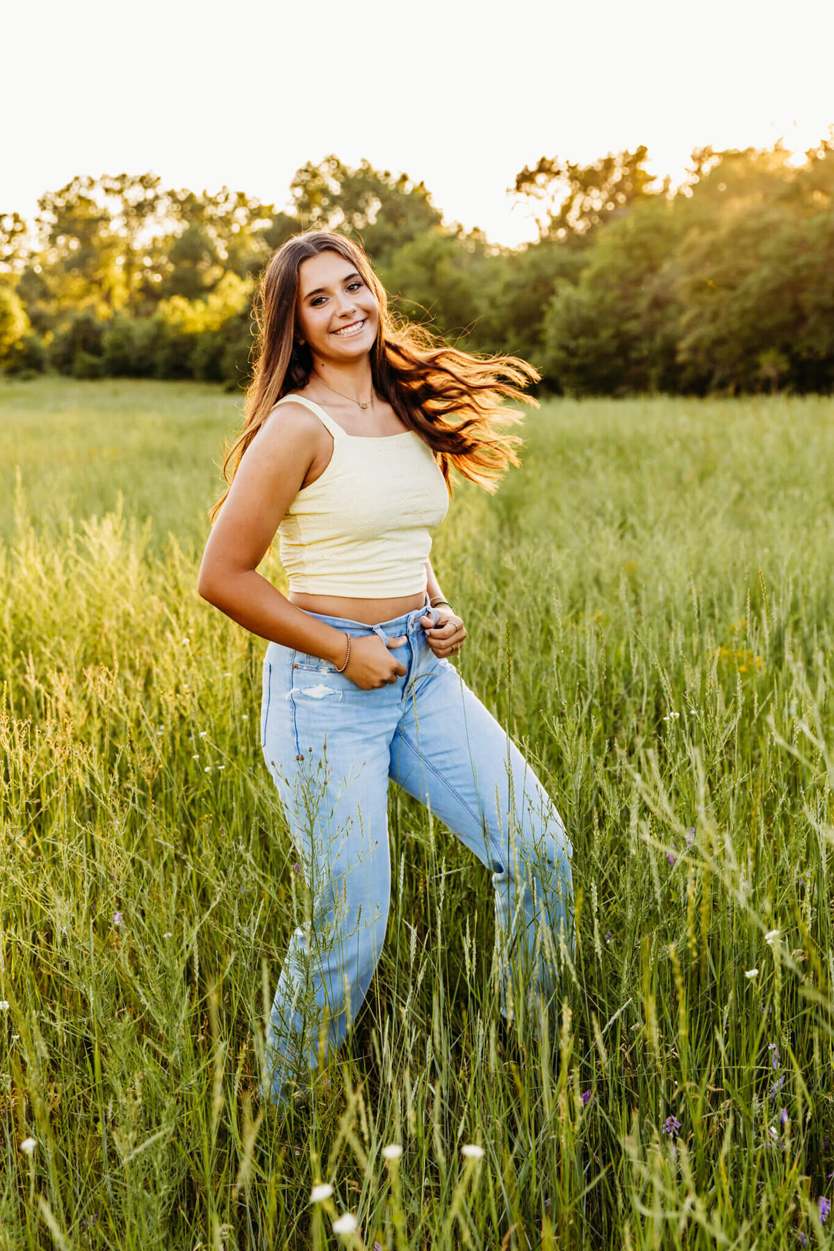 brown haired senior girl rocking back and forth as she smiles for her senior photos