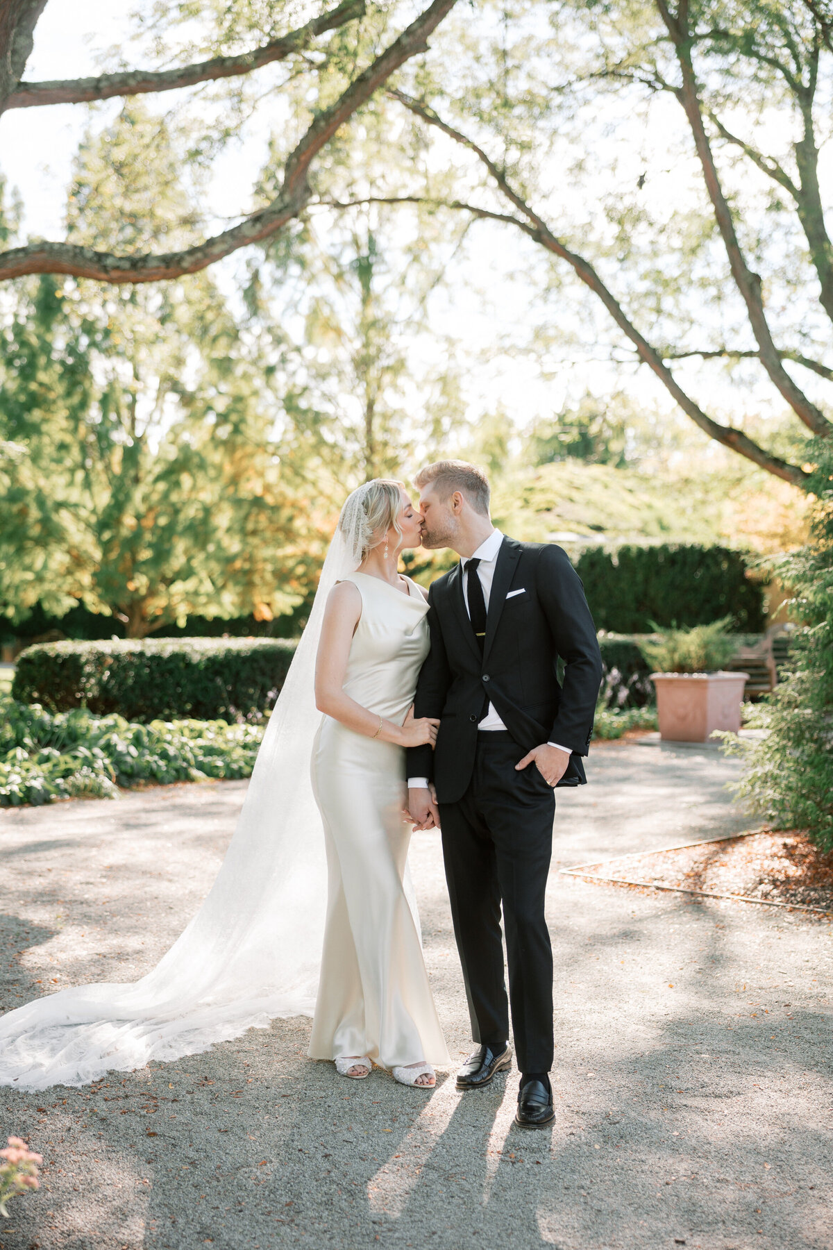 Bride and groom share a kiss under the trees in Dayton, Ohio, wedding ceremony captured by Philadelphia photographer.