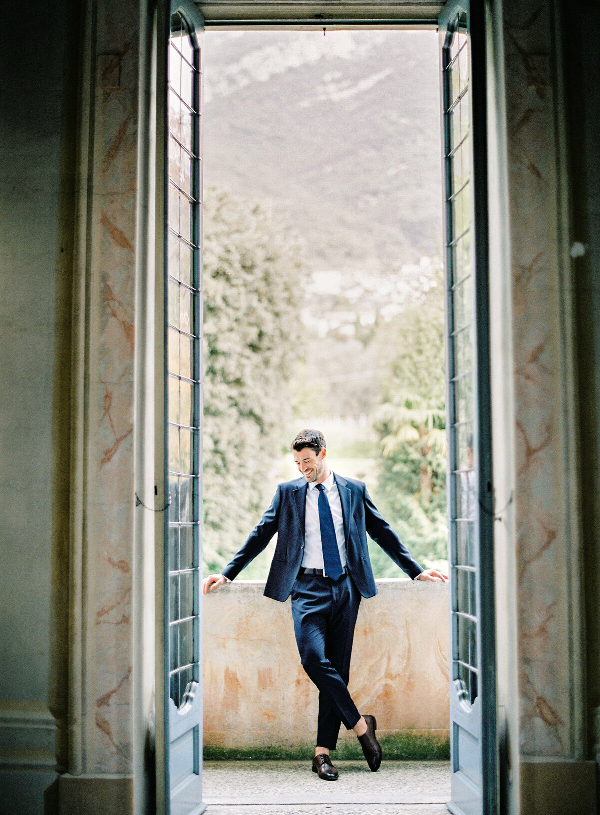 Bride and groom in an intimate moment on the balcony of Villa Sola Cabiati on Lake Como bride in an off the shoulder wedding dress with oversized bow in the back and groom in navy suit during their Lake Como wedding photographed by Italy wedding photographer