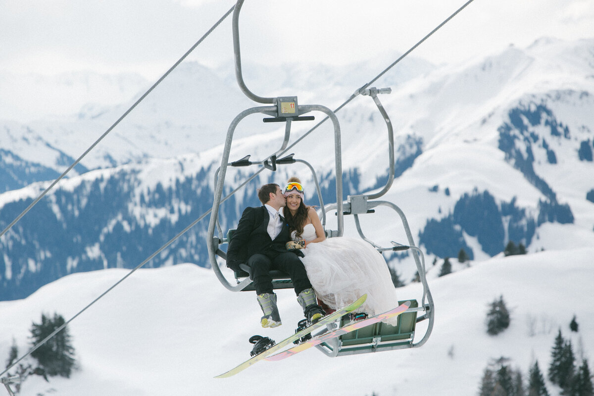 Bride, groom, and friends laughing in snow with snowboards and goggles – après-wedding energy in Kitzbühel by Studio Rose