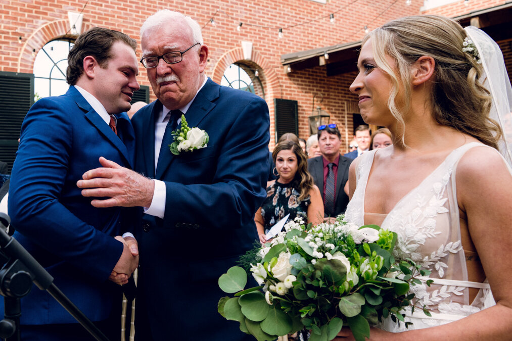A grandfather embracing a groom at a wedding.