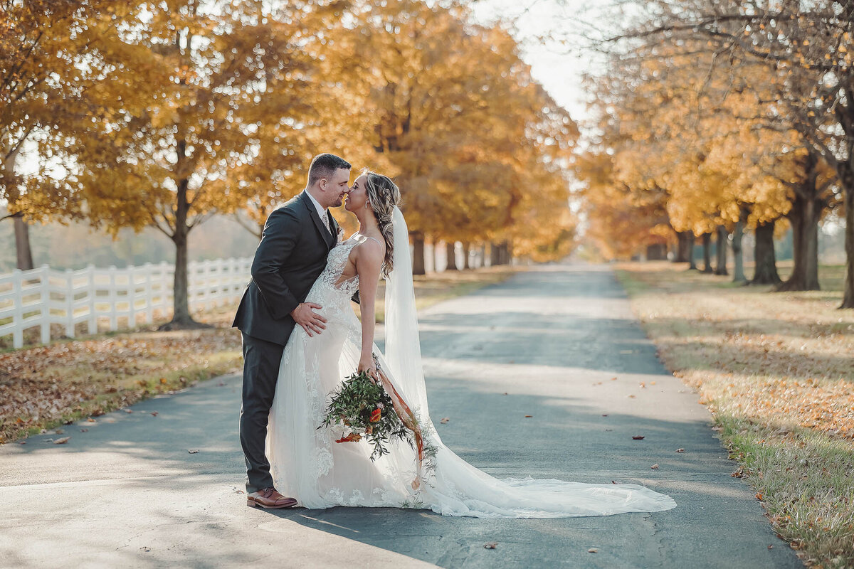 bride and groom kissing outside during the fall