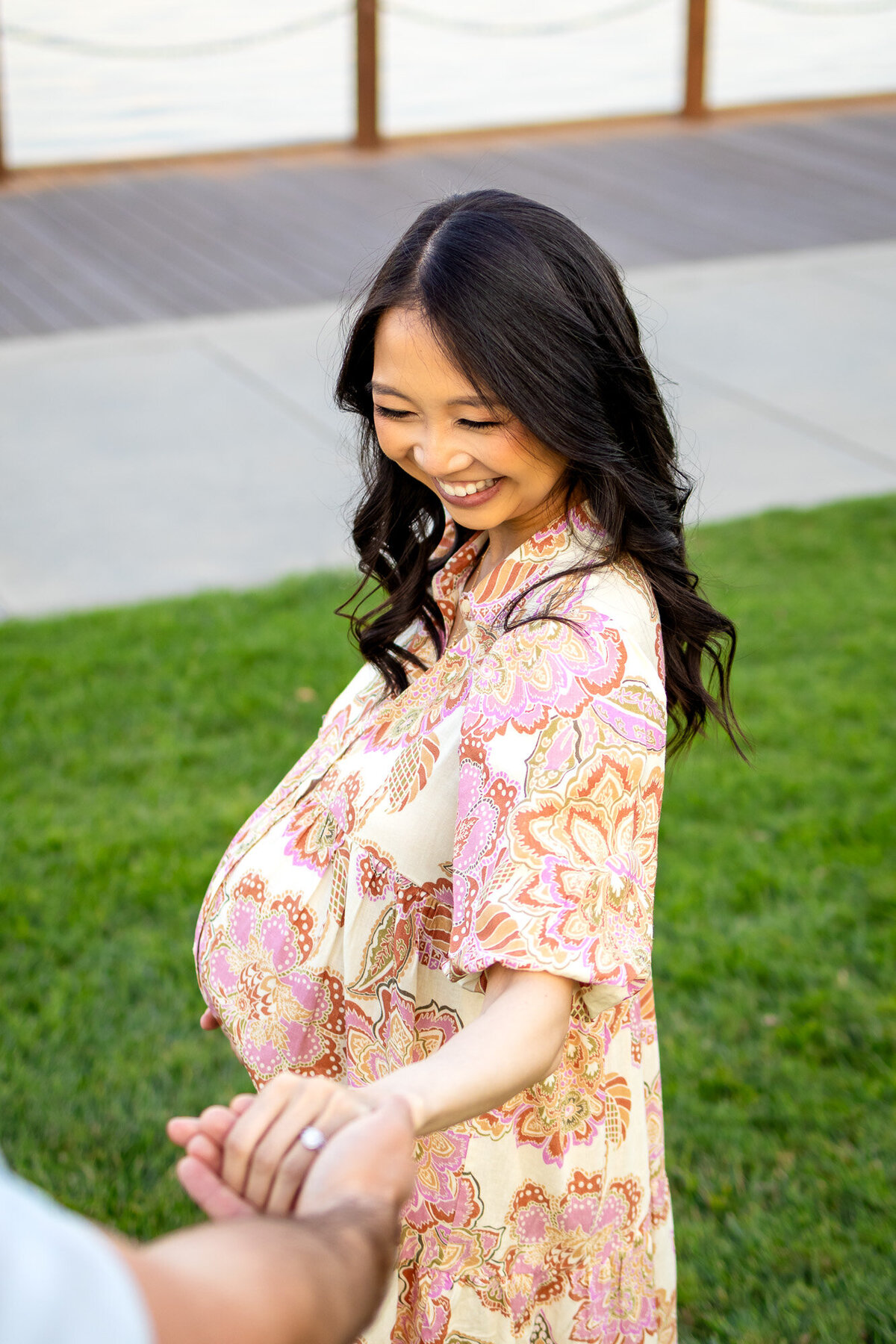 Pregnant woman smiles while reaching out and holding her partner’s hand during a waterfront maternity session — Bay Area Maternity Portfolio - Ellobelle Photography.