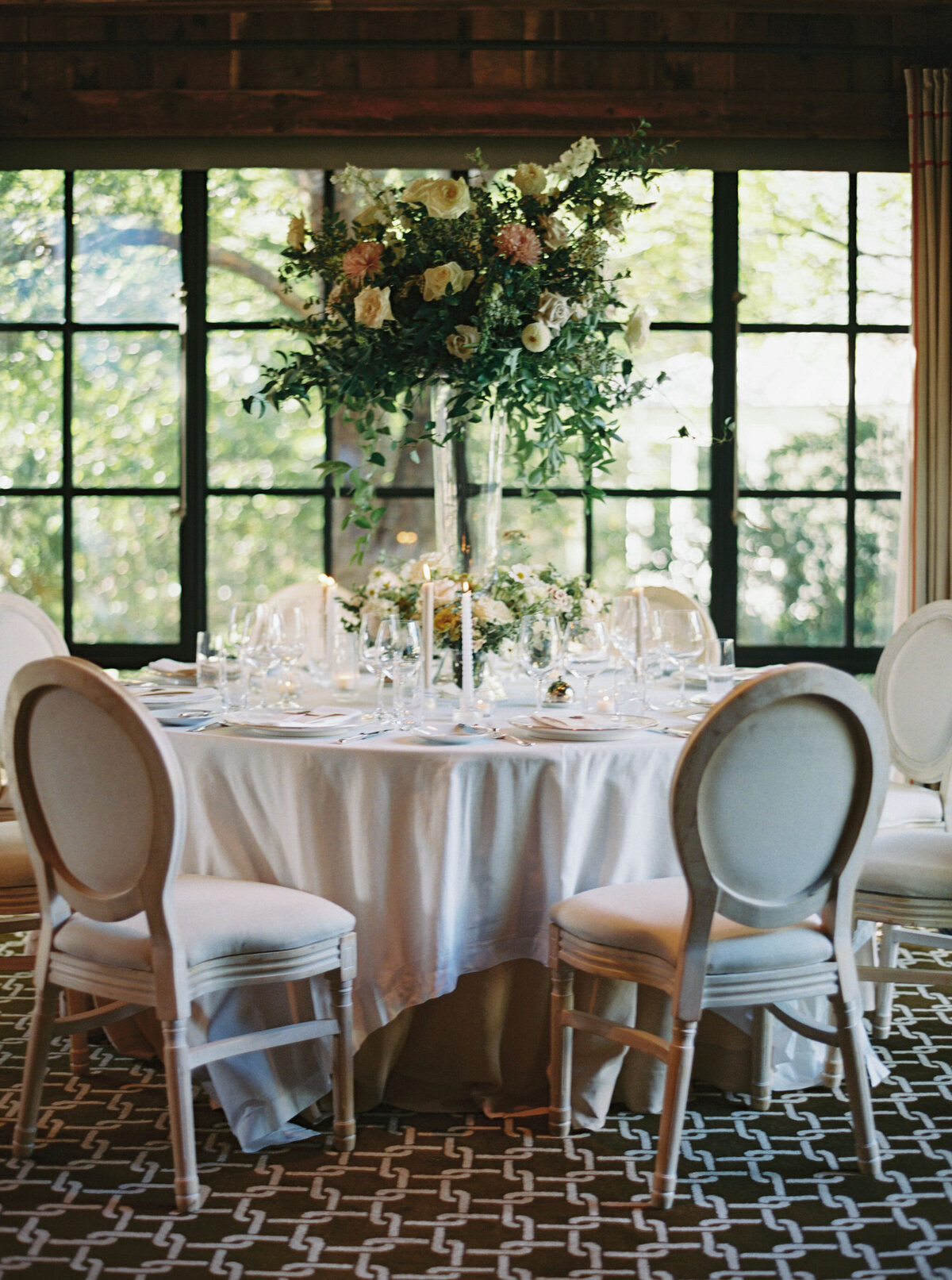 Elegant and timeless floral design for wedding reception tables. Wedding dinner at The Barn on Blackberry Farm. Garden inspired growing floral in colors of cream, white, blush, and green. Whimsical floral design for low centerpieces and elevated arrangements at fall wedding reception. Romantic candlelight and timeless floral design for elegant tablescapes. Destination wedding at Blackberry Farm. Design by Rosemary & Finch Floral Design in Nashville, TN.