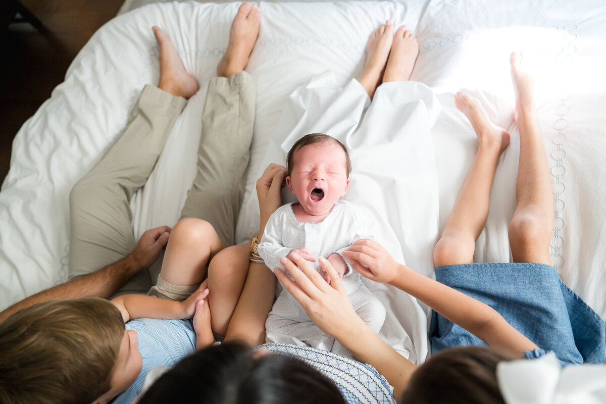 Parents holding newborn in cozy Austin home during lifestyle session.