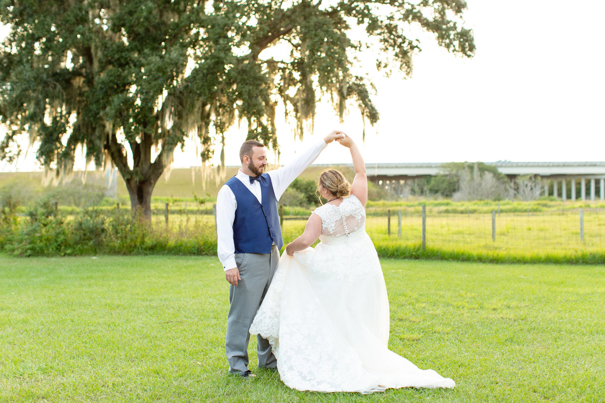 Groom twirls bride in her white wedding dress at sunset on their wedding day in Lakeland, Florida