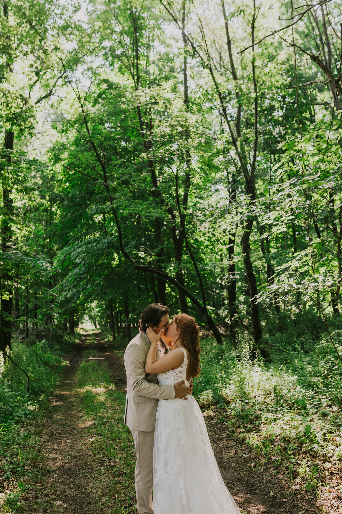 Couple embracing in a lush forest, intimate outdoor engagement photography.