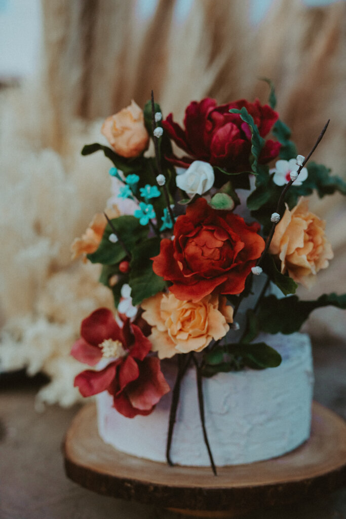 Unique textured two-tiered textured wedding cake, covered in burgundy and peach florals, created by Chartier YYC, elegant cakes & desserts in Calgary, AB, featured on the Brontë Bride Vendor Guide.