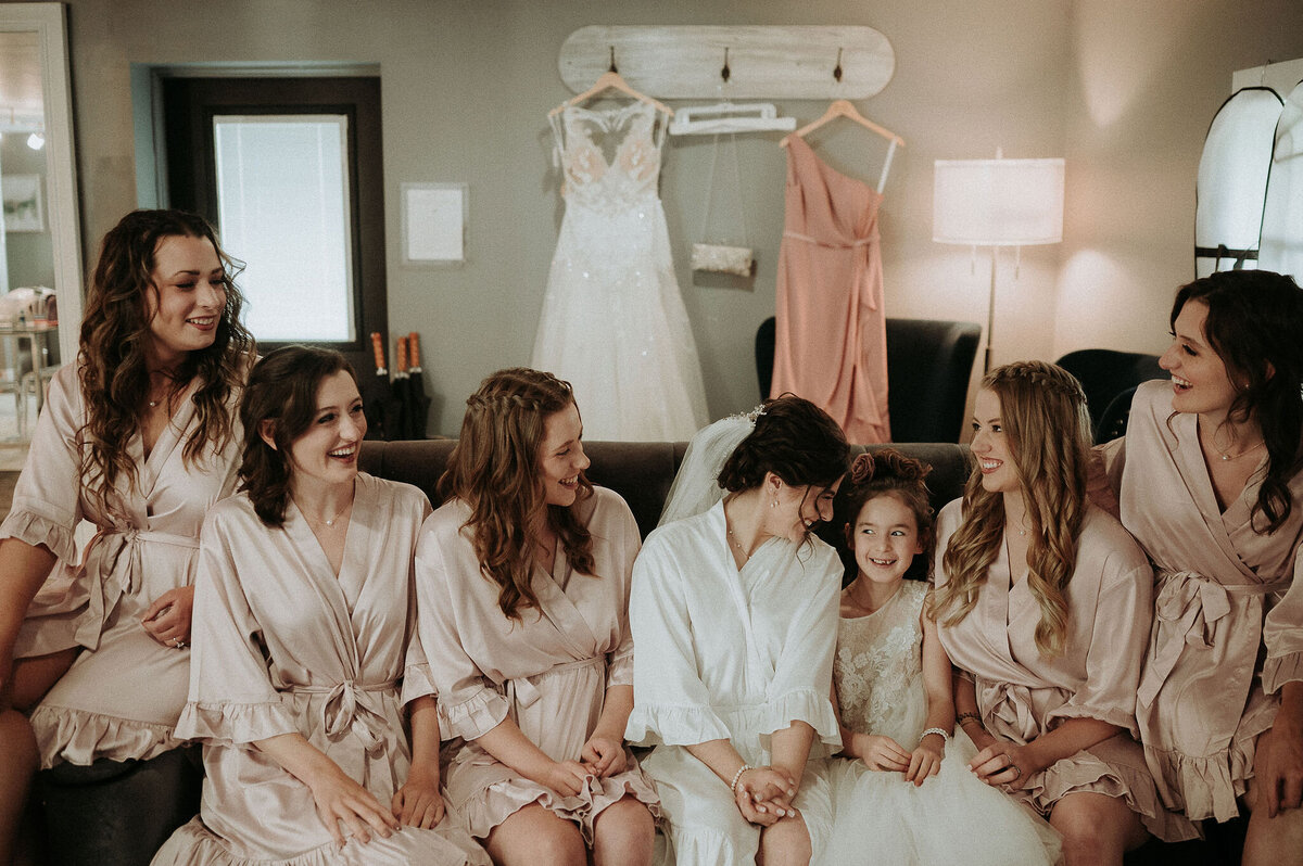 a bride with her bridesmaids dressed in blush color silk robes in the preparation cottage at Willowbrook wedding venue