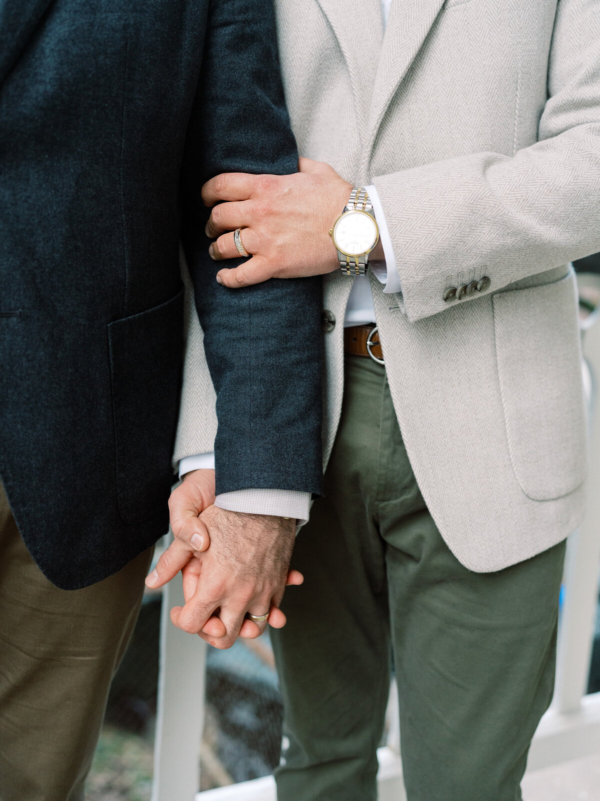 An intimate close-up reveals a couple's hands intertwined, emphasizing their commitment and love, framed beautifully against a serene backdrop showcasing their bond.