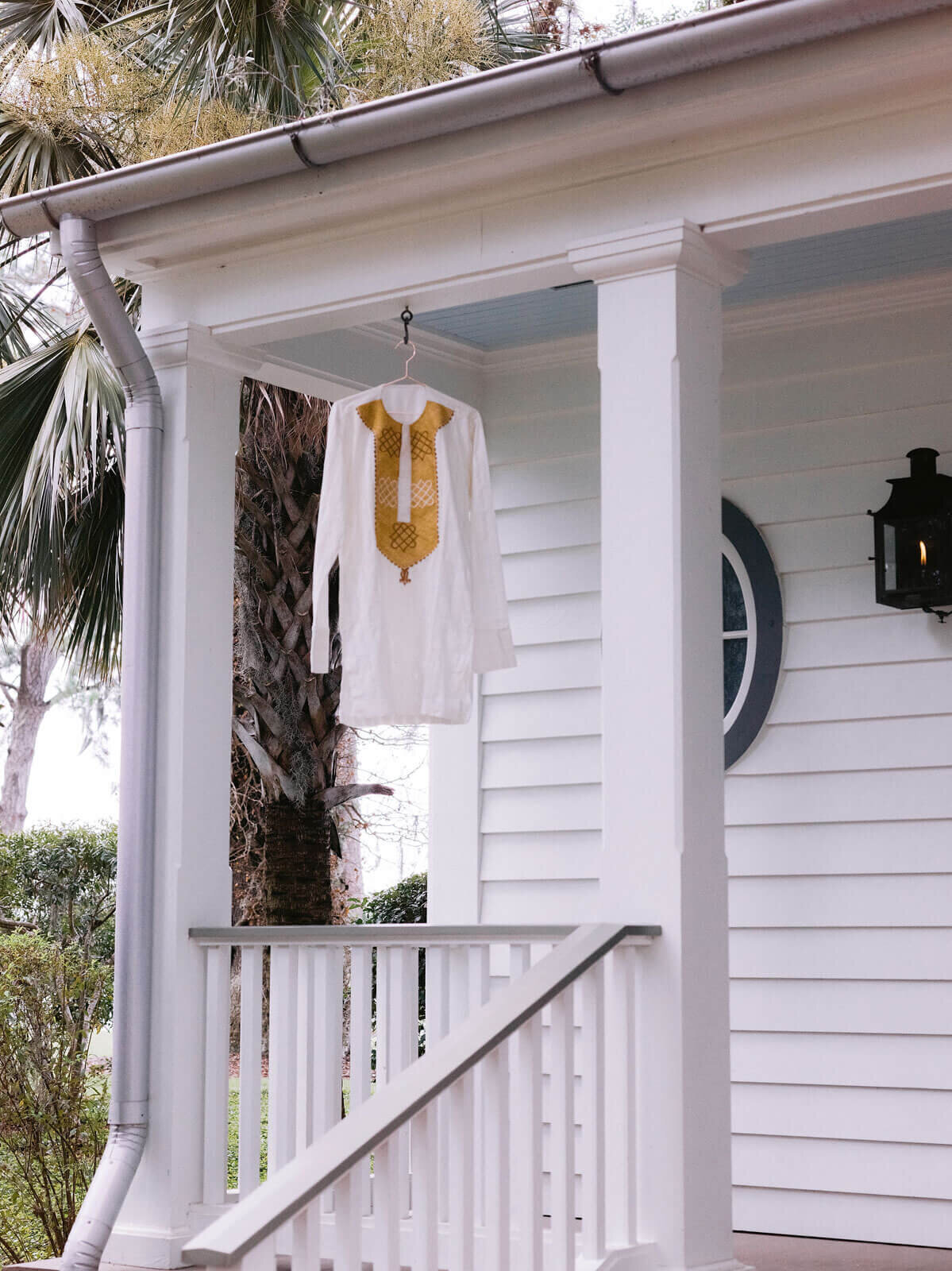 The groom's traditional white African top is hung in front of a house in Montage at Palmetto Bluff. Destination image by Jenny Fu Studio