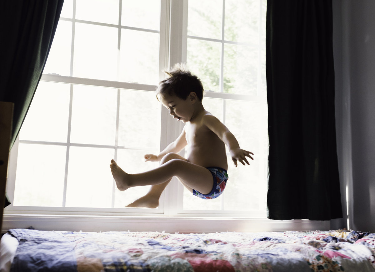 boy jumping on bed
