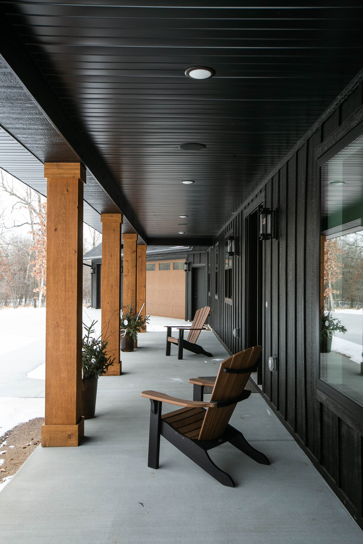 Exterior view of custom home in Elk River, Minnesota with black siding, wood details and front porch built by Cornerstone Custom Builds