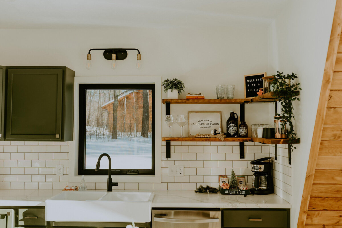 Kitchen sink and open shelving inside of airbnb cabin.