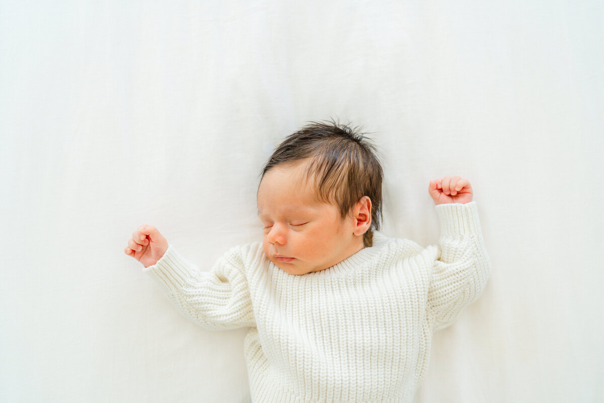a newborn baby lays on a white sheet