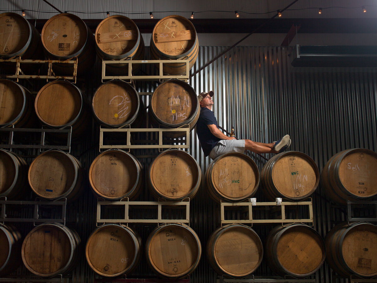 A person sitting on a stack of wine barrels