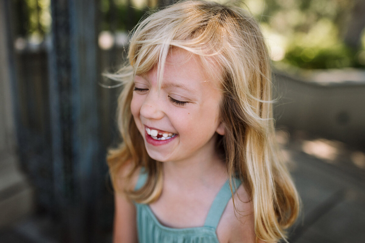 girl in sundress standing in Piedmont park with eyes closed laughing