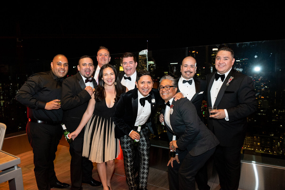 A group of wedding guests smiling on a rooftop