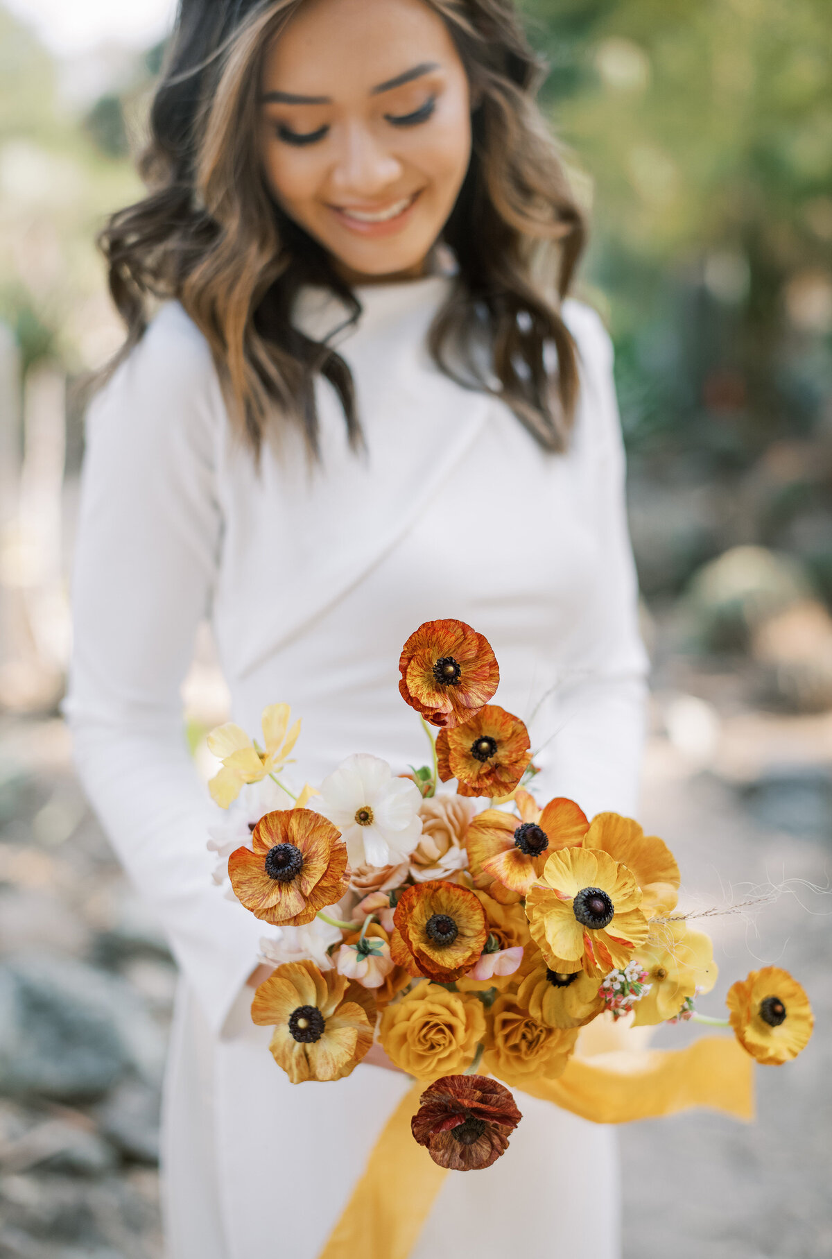 bridal bouquet in shades of burgundy and gold with modern ao dai held by bride at ruth bancroft gardens in walnut creek