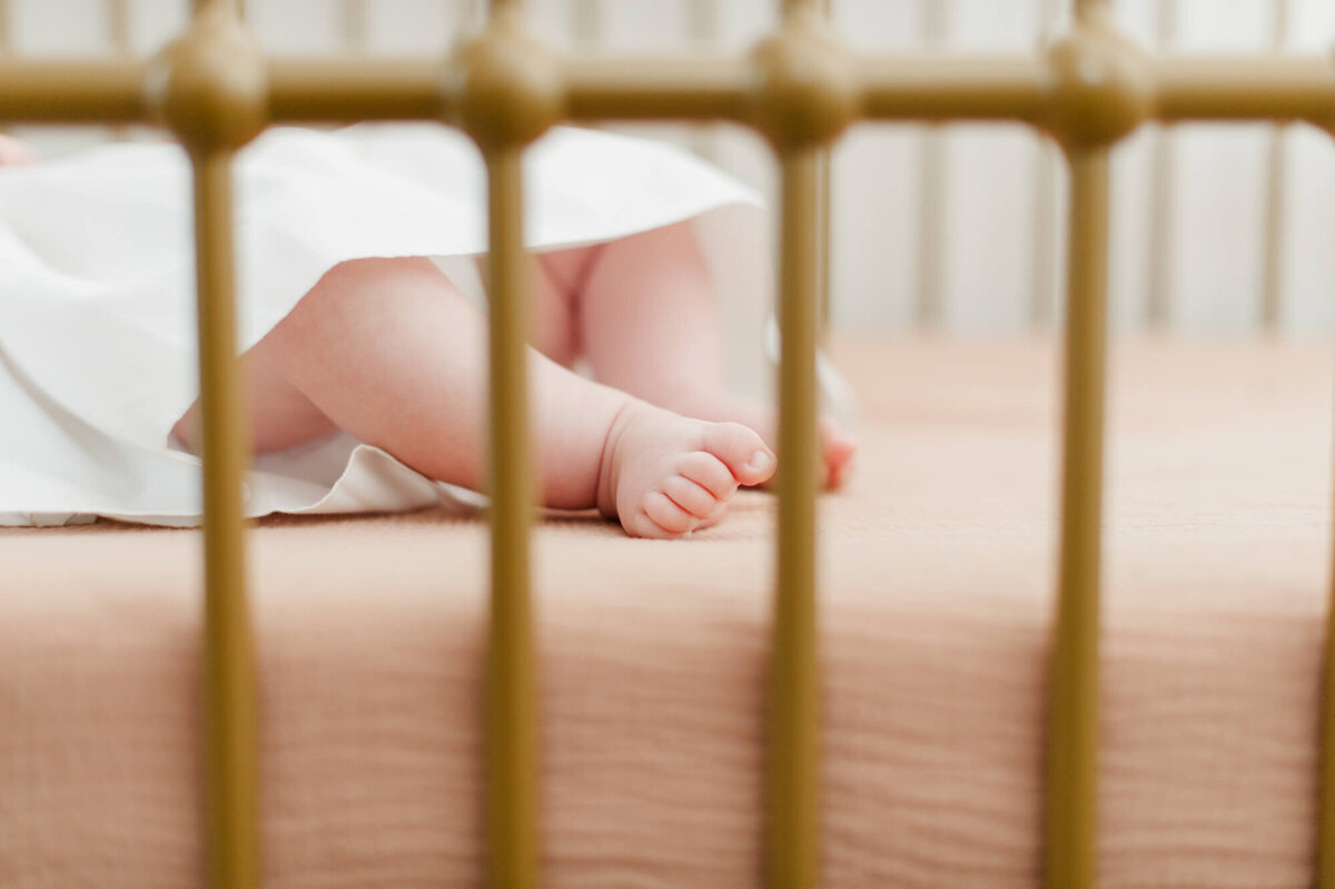 Closeup of newborn toes through the crib rails during her newborn photographer session