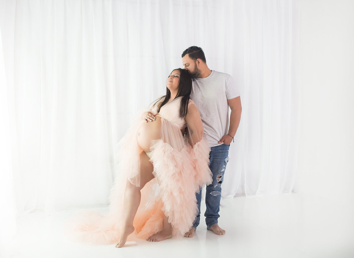 Women wearing pnk gown with husband during maternity photoshoot in Franklin tennessee photography studio